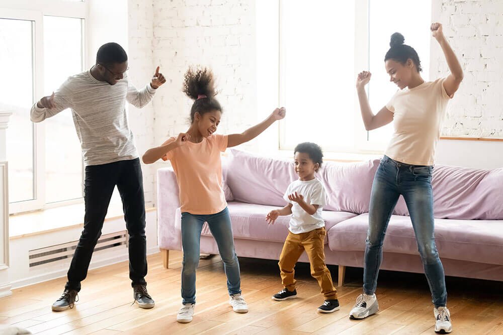 Une mère et un père qui dansent avec leur fils et leur fille dans le salon. 